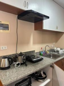 a kitchen counter with a stove and a sink at 7 mins to SM Premiere & Port to Samal - Condo in Davao City