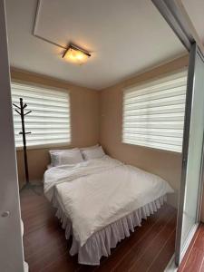 a bedroom with a bed with white sheets and a window at 7 mins to SM Premiere & Port to Samal - Condo in Davao City
