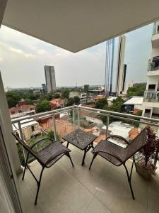 balcón con 2 sillas y vistas a la ciudad en Hermoso Loft Zona Shopping Sol 03, en Asunción