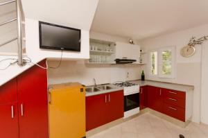 a kitchen with red cabinets and a tv on the wall at House Ancica in Gornje Selo