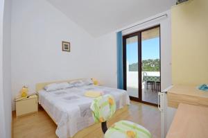 a white bedroom with a bed and a balcony at Apartments and Rooms Barbara in Lastovo