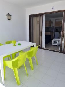 een eetkamer met een witte tafel en gele stoelen bij Sands Beach - Hoy Hotels in Costa Teguise