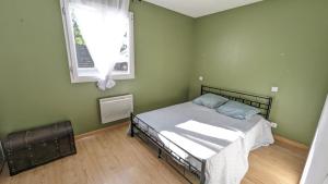 Dormitorio verde con cama y ventana en Gîte maison à Montendre, en Montendre