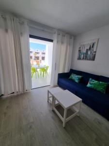 een woonkamer met een blauwe bank en een tafel bij Sands Beach - Hoy Hotels in Costa Teguise