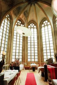 un restaurante con mesas, sillas y ventanas grandes en Kruisherenhotel Maastricht - Oostwegel Collection, member of Design Hotels en Maastricht