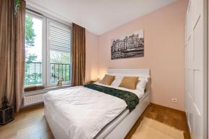 a white bedroom with a large bed and a window at Cracow City Premium Apartment in Kraków