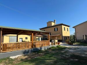 ein Haus mit einer Holzveranda und einem Gebäude in der Unterkunft Casale Il Terranova in Cortona