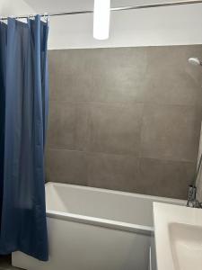 La salle de bains est pourvue d'une baignoire blanche et d'un rideau de douche bleu. dans l'établissement City Center Accommodation - 308, à Reşiţa
