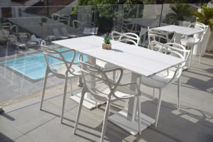 a white table and chairs next to a pool at Hotel La Voile in Bormes-les-Mimosas