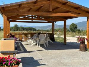 a wooden pergola with white chairs on a patio at Casale Il Terranova in Cortona