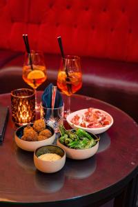 a table with bowls of food and glasses of wine at Kruisherenhotel Maastricht - Oostwegel Collection, member of Design Hotels in Maastricht