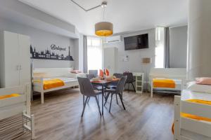 Downtown Apartment House Orange في بودابست: غرفة مع طاولة وكراسي وسريرين