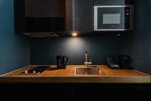a kitchen counter with a sink and a microwave at De Jonker Urban Studios & Suites in Amsterdam