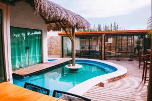 a swimming pool with a deck and a house at Chalé em condomínio beira mar in Barrinha