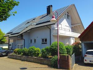 a house with a solar roof with a street light at Gästehaus ALBA - Sie bekommen garantiert Eintrittskarten für den EuropaPark und für Rulantica über uns, zusätzlich zum limitierten Kontingent in Rust