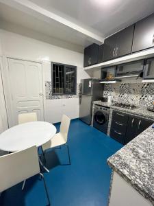 卡薩布蘭卡的住宿－L'Appartement Harmonia Cozy，厨房铺有蓝色的地板,配有白色的桌椅。