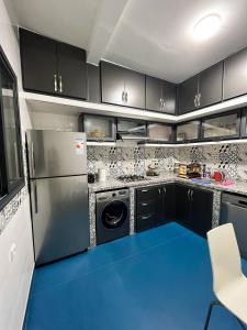 a kitchen with black cabinets and a blue floor at L'Appartement Harmonia Cozy in Casablanca