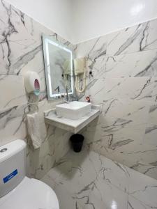 een witte badkamer met een wastafel en een spiegel bij L'Appartement Harmonia Cozy in Casablanca