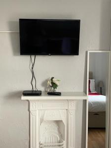 TV de pantalla plana encima de una chimenea blanca en The Old Postie Bed & Breakfast en Annesley