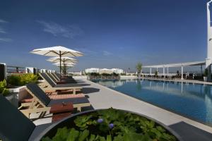 una gran piscina con sillas y sombrilla en Kameo Grand Hotel & Serviced Apartment, Rayong en Rayong