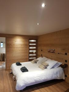 a large white bed in a room with wooden walls at Aux fermes de la Croix, chambres, petits-déjeuners, diners in Hauteluce