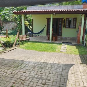 a green house with a hammock in front of it at Casinha Mar e Sol Boiçucanga in São Sebastião