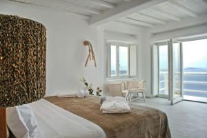 FanariにあるMagnificent Mykonos Villa - Villa Blue Paradise - 8 Bedroom - Private Pool And Bar - Panoramic SeaViewsの白いベッドルーム(大型ベッド1台、テーブル付)