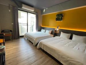 una camera d'albergo con due letti e una parete gialla di Long Lang Homestay a Tainan