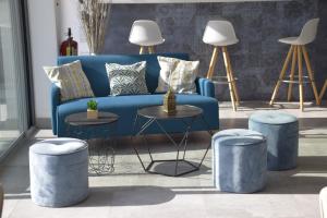 a living room with a blue couch and stools at Hotel La Voile in Bormes-les-Mimosas