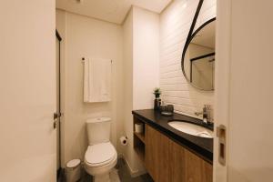 a bathroom with a toilet and a sink and a mirror at Loft perfeito no Parque Una com garagem in Pelotas +26 photos