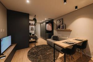 a living room with a couch and a table and a television at Loft perfeito no Parque Una com garagem in Pelotas