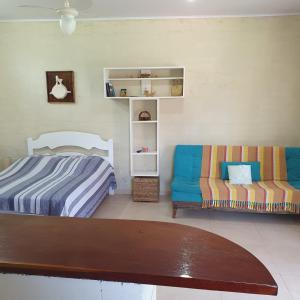 una camera da letto con un letto e un divano di Casinha Mar e Sol Boiçucanga a São Sebastião