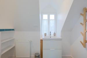 a white bathroom with a sink and a window at Ker Lotig in Locquirec