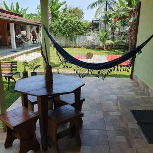 a hammock on a patio with a table and benches at Rancho do Capitão Boiçucanga in São Sebastião