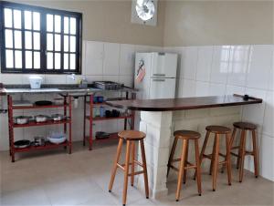a kitchen with three bar stools and a refrigerator at Rancho do Capitão Boiçucanga in São Sebastião