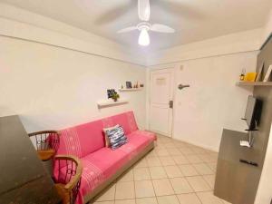 a pink couch in a living room with a ceiling fan at Ocean Flat 607 in Vila Velha