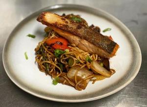 a white plate of food with noodles and a sausage at The Black Swan Inn in Norwich