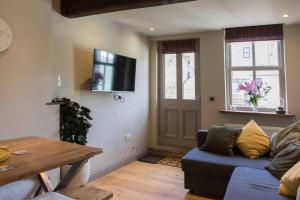 a living room with a blue couch and a tv on the wall at 3 George Street Addingham in Addingham