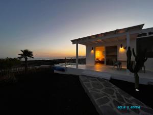 una pequeña casa con una puesta de sol en el fondo en CASA TIE' Lanzarote vista mar - piscina relax - adults only, en Tías