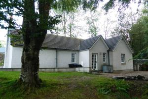 a white house with a tree in front of it at River Cottage in Turriff