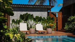 2 chaises et une piscine dans une cour ornée de plantes dans l'établissement Vila Sal Noronha, à Fernando de Noronha