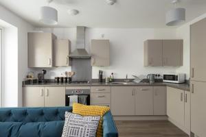 cocina con armarios blancos y sofá azul en Central 1-Bed perfect for you By Valore Property Services en Milton Keynes