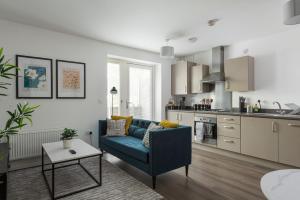 a living room with a blue couch and a kitchen at Central 1-Bed perfect for you By Valore Property Services in Milton Keynes