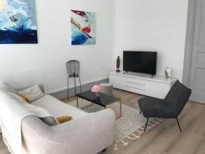 uma sala de estar com um sofá branco e uma televisão em 3 M en hyper centre em Montauban