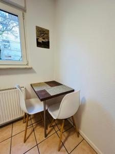 une table à manger avec deux chaises blanches et une fenêtre dans l'établissement 1-2 Pers nur 0,3 km zur City von Wuppertal-modern, à Wuppertal