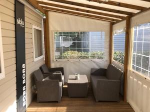 a porch with chairs and a table and a window at camping les sables du midi in Valras-Plage