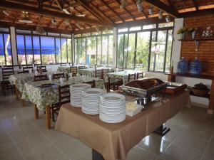 Pousada Sino dos Ventos في São Sebastião do Rio Verde: غرفة طعام مع طاولة عليها لوحات