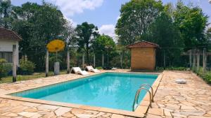 a swimming pool in a yard with a stone patio at Pousada Sino dos Ventos in São Sebastião do Rio Verde