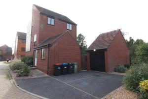 a brick building with a garage and two trash cans at Swanwick House in Broughton