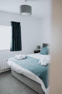 a bedroom with a large bed with blue sheets and a window at The Fox and Hounds in Banc-y-felin